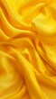 A yellow fabric with a pattern of waves. The fabric is folded and has a smooth texture. The color yellow is dominant in the image, giving it a warm and inviting feel