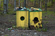 dwa pełne pojemniki na śmieci w lesie - śmietnik