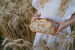 Close-up of rye bread in the hands of a blonde girl in a field of rye