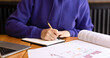 Woman's hands writing notes with pen in notebook, books and textbooks on table. Girl studying, student in class, writing notes in notebook, space for copy, graphics on paper
