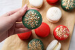 Woman with decorated Christmas macaron at table, closeup