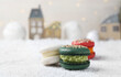 Different decorated Christmas macarons on table with artificial snow