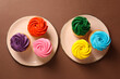 Delicious cupcakes with bright cream on brown background, flat lay
