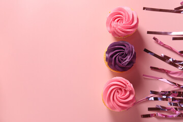 Wall Mural - Delicious cupcakes with bright cream and confetti on pink background, flat lay. Space for text