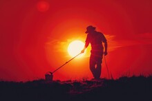 Man Using Metal Detector On Hill At Sunset. Suitable For Outdoor Hobby Concept
