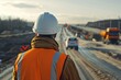 Civil engineer supervising road construction. Construction project. Road construction. Crews working on the road. White hard hat and vest. The motorway construction