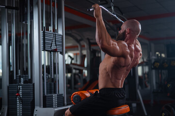 Wall Mural - Caucasian man doing lat pull-downs on a machine. 