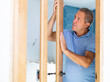 Ordinary elderly man checks the quality of the installed new wooden door