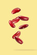 Red kidney beans falling on yellow background.