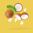 Coconut and palm leaves falling on yellow background.
