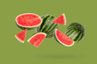 Falling Watermelon slice with cut and half isolated on green background.