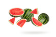 Watermelon with half and slices falling on white background