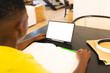 At home, African American boy holding green pen, looking at a tablet, copy space