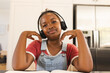 African American girl wearing headphones, enjoying music at home