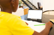 An African American boy in yellow shirt writing during video call at home, copy space