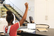 African American girl in headphones raises hand in tablet-based online lesson, copy space