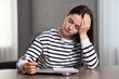 © New Africa - Overwhelmed woman sitting at wooden table with laptop, glasses and stationery indoors