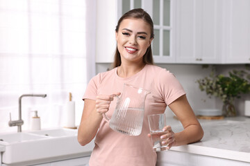 Poster - Happy woman with jug and glass of water in kitchen