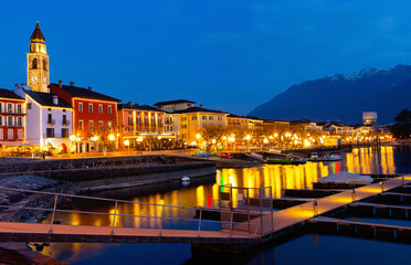 Wall Mural - View of embankment in Ascona, canton of Ticino, Switzerland. Houses along waterfront, turned on city lights in evening.