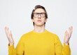 A man in a yellow sweater raises his arms to the sides in surprise, a gesture of amazement.