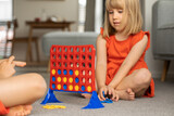 Fototapeta Kuchnia - Cute little girl strategizing in Connect Four. Logic game