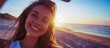 Euphoric young woman shares her joy through a selfie, with the golden glow of the sunset on the beach