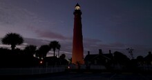 Low Angle Drone Footage Of Tall Ponce De Leon Inlet Lighthouse And Silhouette Trees Against Sky During Sunset In Florida