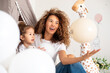© kanashkin - Curly mother and daughter playing in children's room with toys and tent