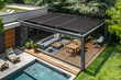 Top view of a modern black bio climatic pergola on an outdoor patio with a pool, lounge chairs, and lush greenery in the garden.