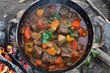 Cook goulash with tomatoes beef onions garlic celeriac and carrots over fire for four hours