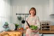 © Kawee - Portrait of Caucasian senior woman hold a bowl of vegetables in house.