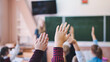 Elementary school students raise their hands during class.