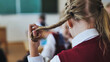 A girl touches a ponytail of her hair during class.