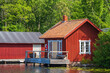 Old red wooden cottage by the water with a jetty