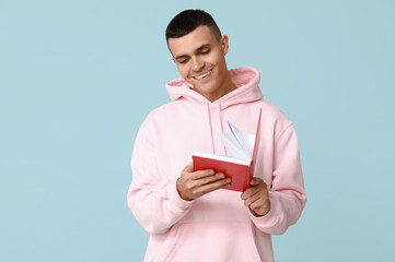 Poster - Handsome young man reading book on blue background