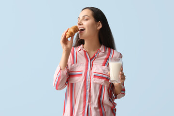 Poster - Young woman with glass of tasty milk and croissant on blue background