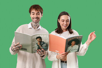 Wall Mural - Young couple reading magazines on green background
