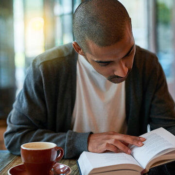 Man, coffee and reading book at cafe in table for reading novel or story for knowledge. Restaurant, literature and break in desk with cup of tea to chill, relax and lunch with chapter for mindfulness