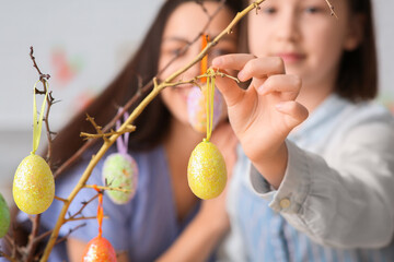 Canvas Print - Little girl and her mother decorating tree branches with Easter eggs at kitchen