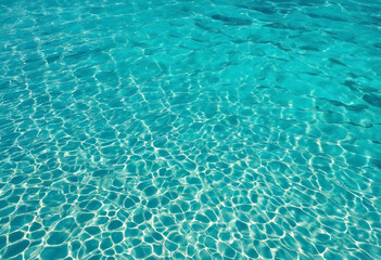 Beautiful turquoise blue ocean water surface with light reflections and highlights. Texture of water close-up macro