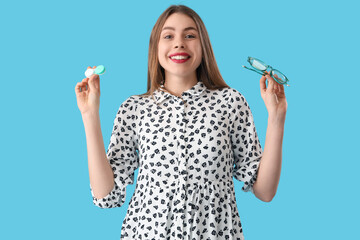 Canvas Print - Young woman with contact lenses and eyeglasses on blue background