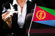 business woman holds toy plane travel bag and flag of Eritrea

