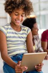 Wall Mural - Happy african american preeteen girl using digital tablet for education, fun at home. Family concept