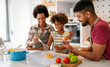 Happy african american family preparing healthy food in kitchen, having fun together on weekend