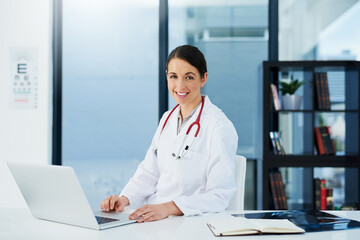 Canvas Print - Doctor, woman and portrait at desk with laptop, medical research and planning hospital schedule. Female person, smile and confident for healthcare, cardiologist and clinic website for expert medicare