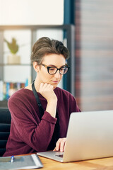 Office, laptop and woman at creative agency with thinking, reading and online market research at startup. Website, digital professional and businesswoman at computer checking review, email or report.