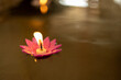 Colored flower-shaped candles with flames are floating in the water.