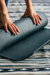 © simona - Close up of woman closing her yoga mat after finishing healthy lifestyle training session alone at home or gym. Concept of sport fitness lifestyle female people. Indoor workout daily routine