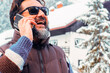 One happy mature man talking at the phone in outdoor snow mountains scenic place enjoying winter season and holiday vacation. Positive smart people using cell outdoor.  Concept of mountain tourism