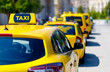 Yellow taxis are lined up on the street in the city, with a blurred background